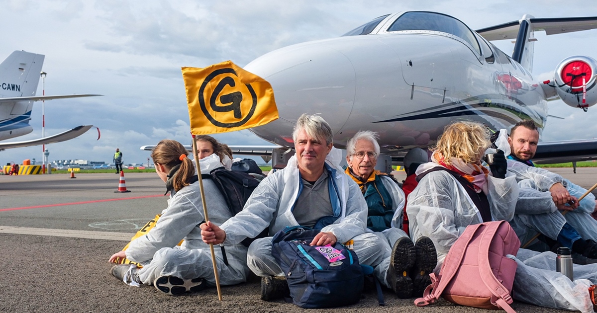 그린피스와 멸종저항의 기후 활동가들이 항공기 바퀴 앞에 앉아 전용기 운항 축소를 촉구하고 있다. (사진 Extinction Rebellion)/뉴스펭귄