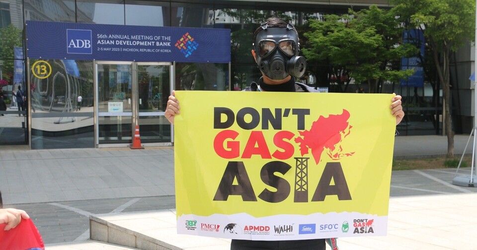 4일 인천 아시아개발은행 연차총회장 앞에서 한 환경단체 활동가가 피켓을 들고 있다. (사진 Don't Gas Asia 트위터)/뉴스펭귄