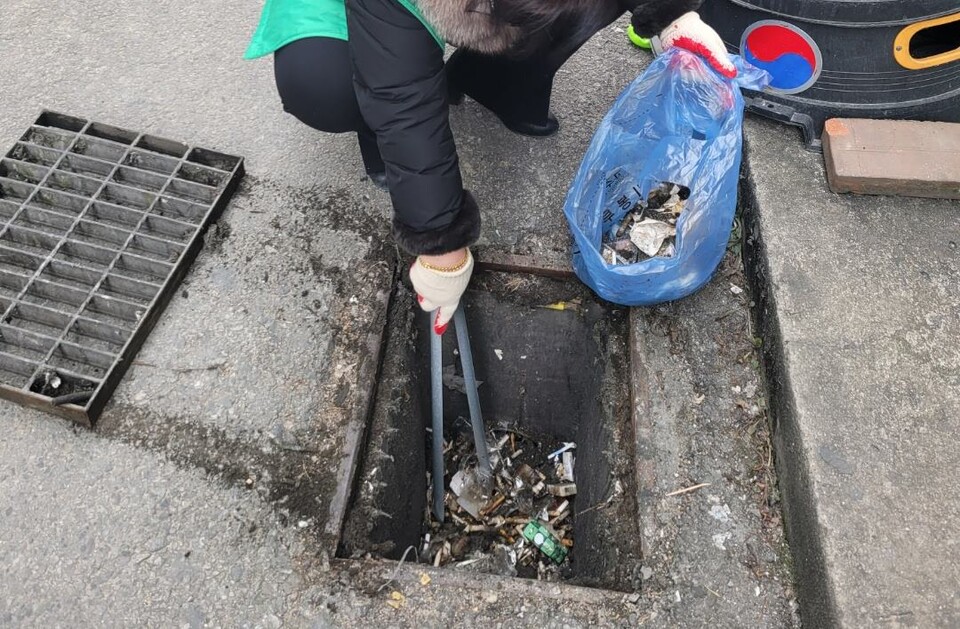 빗물받이의 꽁초와 쓰레기를 치우고 있는 시민. (사진 충남 공주시 보도자료)/뉴스펭귄