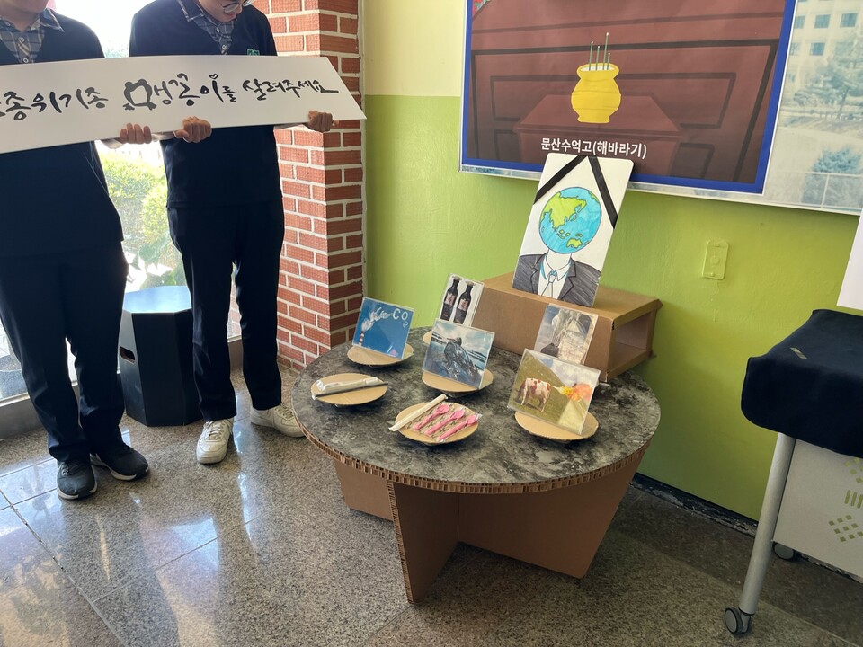 지구의 얼굴을 한 영정 사진 앞에 매연이 하늘로 올라가고 있는 사진, 각종 플라스틱 쓰레기, 기름 유출로  몸이 까맣게 덮인 새의 사진 등이 제사상으로 전시됐다. (사진 유호연 인턴기자)/뉴스펭귄