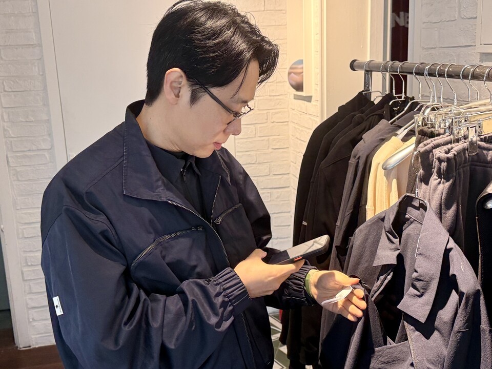 노 대표가  CARE ID의 디지털 제품 여권(DDP)을 스캔하고 있다. 인터뷰 당시 안에 입고 있는 셔츠도 DDP가 부착된 같은 제품. (사진 곽은영 기자)/뉴스펭귄