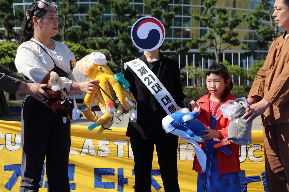 지난 6월 5일 환경의날을 맞아 플뿌리연대가 제주도민들과 함께 새 정부에 오염된 해양생물인형을 건네며 플라스틱 생산 감축을 촉구하는 퍼포먼스를 진행하고 있다. (사진 플뿌리연대)